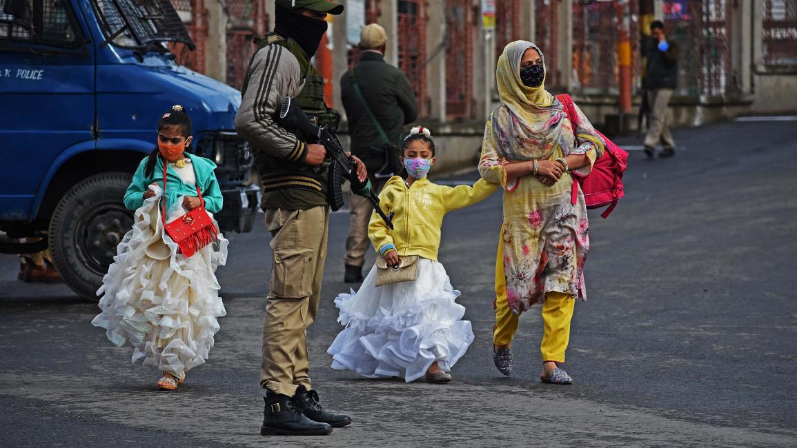 طفلتان مع والدتهما اليوم في كشمير حيث شددت السلطات تدابيرها لكبح تفشي وباء "كوفيد-19" (فيصل خان/الأناضول)