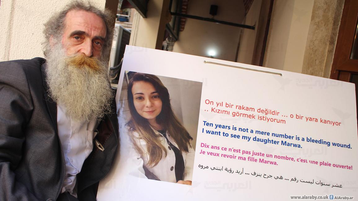 السوري عمار الشيخ حيدر يحمل صورة ابنته (العربي الجديد)