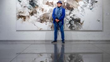 الفنان جان بوغوصيان امام لوحة من لوحاته في معرض الدوحة (العربي الجديد)
