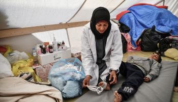 تقدم العلاج للطفل داخل الخيمة (عبد زقوت/ الأناضول)