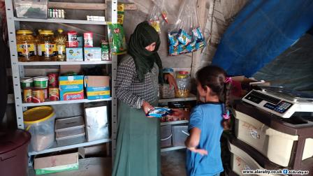 نازحة تقتطع جزء من خيمتها في مخيم شمالي إدلب لبيع سلع غذائية لإعالة أسرتها (العربي الجديد)