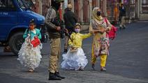 طفلتان مع والدتهما اليوم في كشمير حيث شددت السلطات تدابيرها لكبح تفشي وباء "كوفيد-19" (فيصل خان/الأناضول)