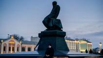 رجل بكمامة الكورونا تحت تمثال دوستويفسكي في موسكو (Getty)