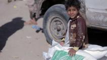 طفل يمني نازح يجلس على أكياس من المساعدات الغذائية في مأرب (عبد الله القادري/فرانس برس)