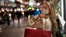 Happy woman Christmas shopping and wearing a facemask while carrying bags â COVID-19 pandemic concepts