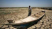 An Iraqi man walks past a canoe siting on dry, cracked earth in the Chibayish marshes near the southern Iraqi city of Nasiriyah on June 25, 2015. Marsh areas in southern Iraq have been affected since the Islamic State group started closing the gates of a dam on the Euphrates River in the central city of Ramadi, which is under the jihadist group's control. AFP PHOTO / HAIDAR HAMDANI (Photo by HAIDAR HAMDANI / AFP) (Photo credit should read HAIDAR HAMDANI/AFP via Getty Images)