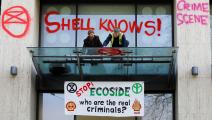 ناشطان يخطّان عبارات احتجاجية، من بينها "أقفوا الإبادة البيئية"، على واجهة مبنى شركة "شل" النفطية في لندن، نيسان 2019 (Getty)