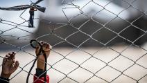 يدا طفل على سياج في منطقة نزاع (دليل سليمان/ فرانس برس)