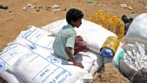 طفل يمني ومساعدات من برنامج الأغذية العالمي في اليمن (عيسى أحمد/ فرانس برس)