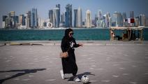 شابة وكرة قدم في الدوحة في قطر قبل المونديال (آن-كريستين بوجولا/ فرانس برس)