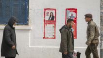 مواطنون أمام إعلانات انتخابية في العاصمة، الاثنين (ياسين القائدي/الأناضول)