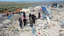 سكان فوق أنقاض منزل في بلدة حارم السورية (عمر حاج قدور/ فرانس برس)