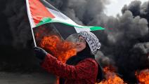 متظاهرة ترفع العلم الفلسطيني أثناء مظاهرة في الضفة الغربية (جعفر أشتيه/فرانس برس)