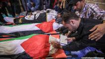 شاب فلسطيني يتلو آيات من القرآن أمام جثامين الشهداء (العربي الجديد)