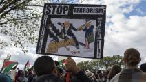 	 متظاهر في واشنطن يرفع كاريكاتير لكارلوس لطّوف (بروبال رشيد / Getty)