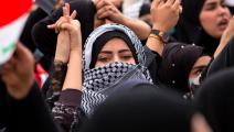 شابة عراقية والكوفية الفلسطينية في تظاهرة سابقة في العراق (حسين فالح/ فرانس برس)