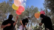 فلسطينيون ملثمون يستعدون لإطلاق بالونات حارقة بالقرب من السياج الحدودي شرق خان يونس (سعيد خطيب / فرانس برس) 