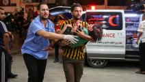 مُسعِف فلسطيني يحمل طفلاً جريحاً إلى مستشفى في خانيونس، إثر غارة صهيونية، 27 الشهر الماضي (Getty)