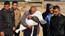 فلسطينيون يحملون جثة طفل وسط الحرب على غزة (محمود الهمص/ فرانس برس) 