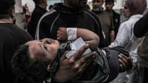 رجل يحمل طفلاً أصيب في غارة جوية إسرائيلية على مستشفى النجار في رفح، 20 آذار/ مارس 2024 (Getty)