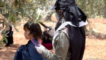 متطوعة تحلق شعر أحد الأطفال بمخيمات ادلب (العربي الجديد)