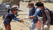 متطوعان يمنيان يعقمان يدي أحد الأطفال في صنعاء (Getty)