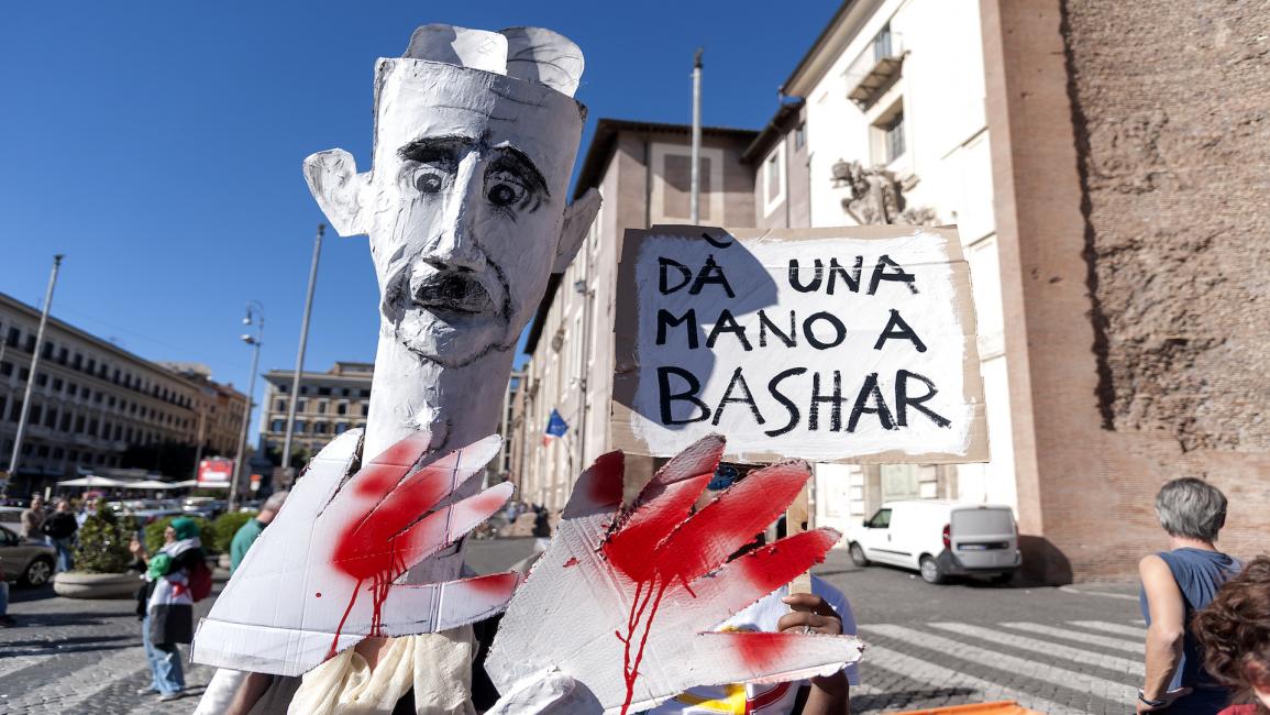 دمية تمثل بشار الأسد ويداه ملطختان بالدماء خلال مظاهرة في روما في 7/ أكتوبر/ تشرين الأول 2017 (Getty)