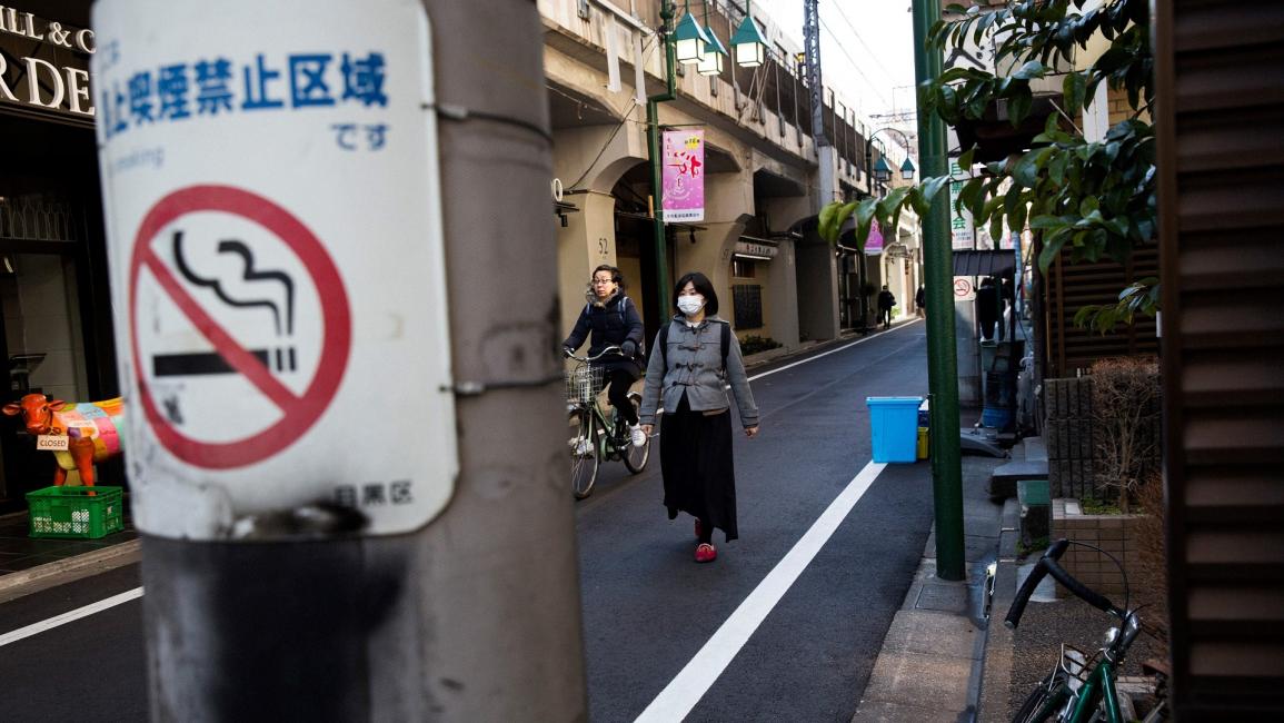 امرأة على دراجة هوائية وعلامة منع التدخين في اليابان