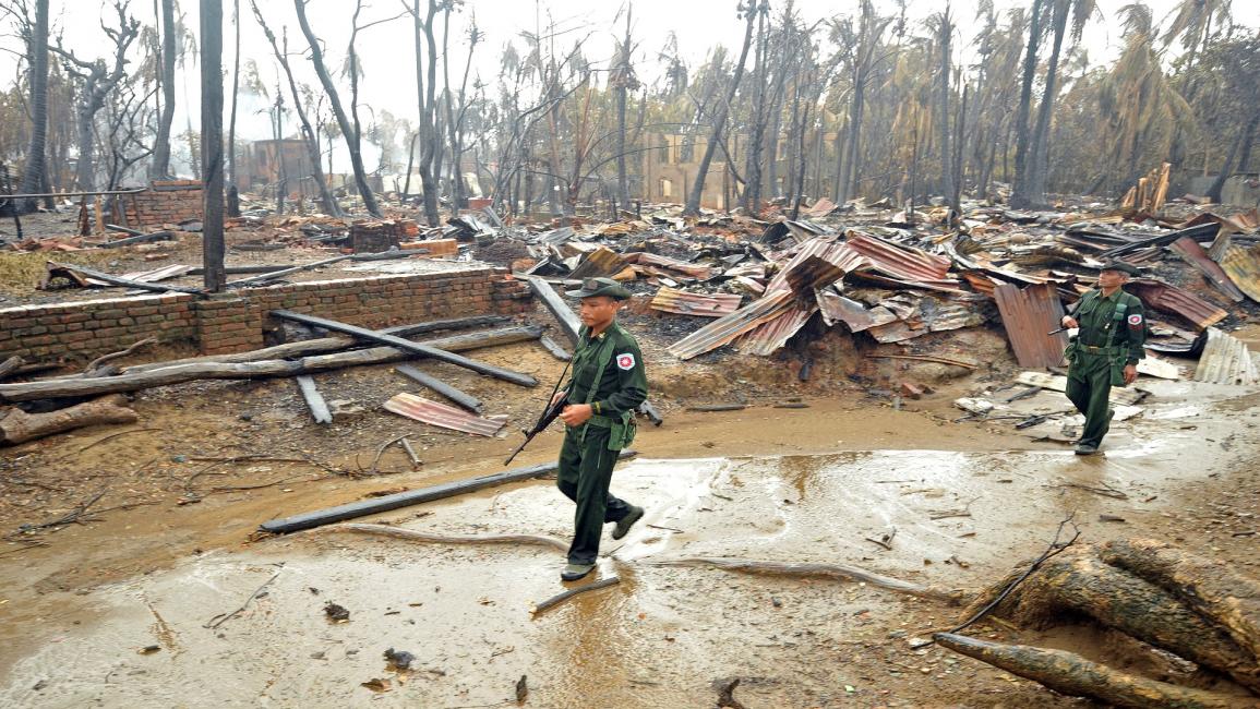 عنصران من الجيش البورمي أمام الدمار بإقليم راخين(فرانس برس)