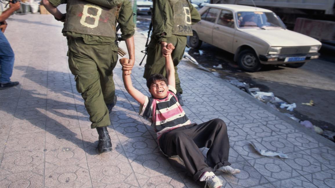 جنود إسرائيليين يعتقلون طفلاً فلسطينياً (بيتر تورنلاي/Getty)