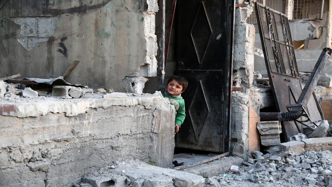 طفل سوري يراقب من منزل مدمر بزملكا (محمد إياد/Getty)