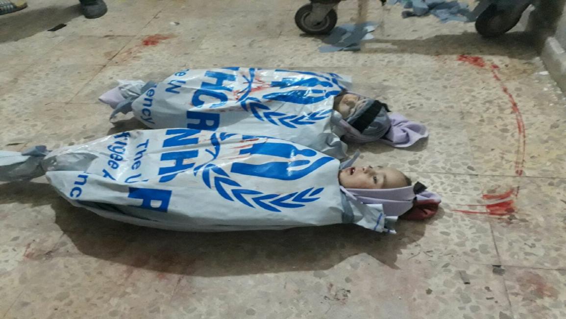 تكفين جثامين أطفال في الغوطة الشرقية بشعار مفوضية اللاجئين(فيسبوك)
