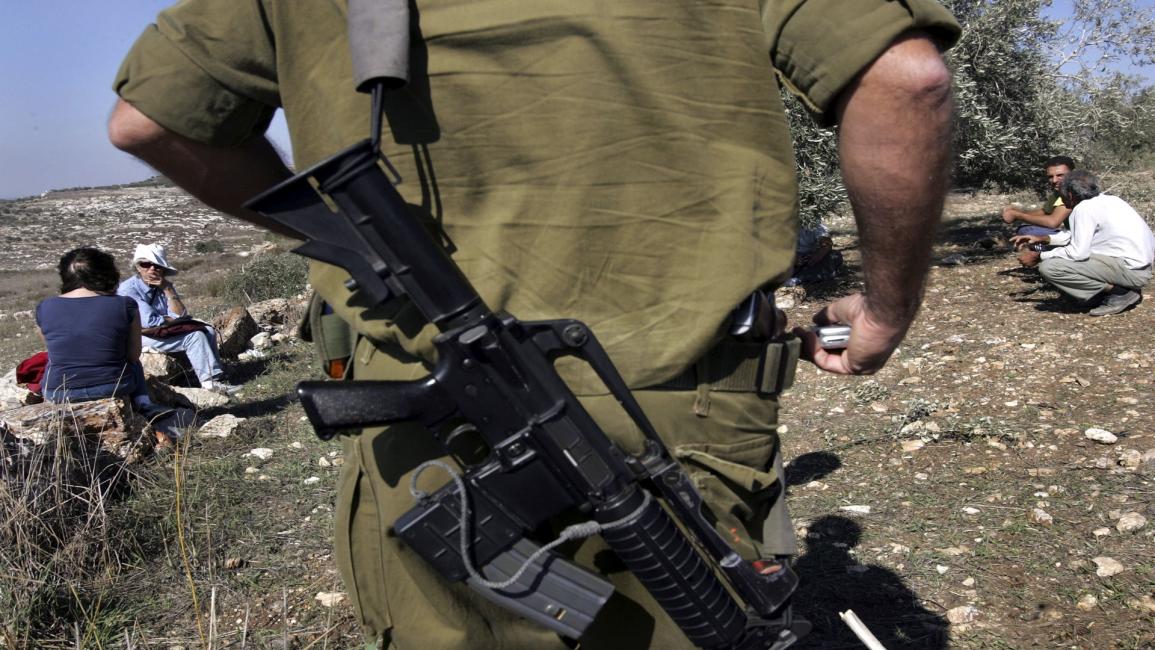 جندي إسرائيلي يقتحم أرضا زراعية فلسطينية (ديفيد سيلفرمان/Getty)