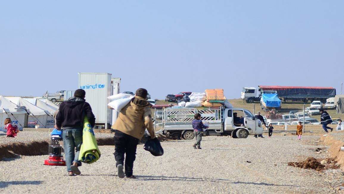 العراق-مجتمع- نازحون يغادرون المخيم في الموصل (هيمن حسين/الأناضول)