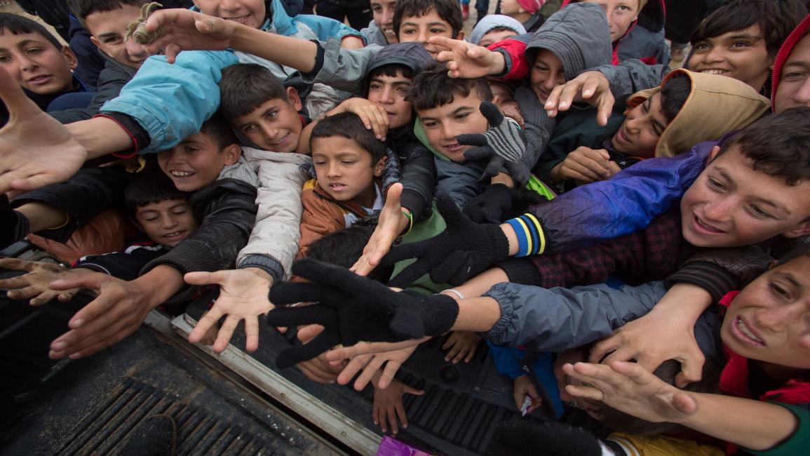 أطفال نازحون في العراق يتهافتون على المساعدات(مات غاردي/Getty)