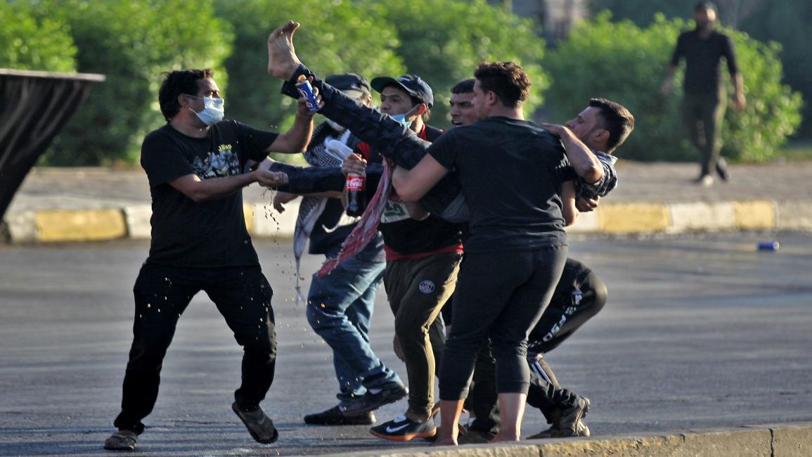 محتجون ينقلون جريحاً في بغداد (أحمد الربيعي/ فرانس برس)