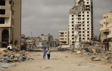 فلسطينيون يسيرون وسط الأنقاض في غزة، 27 مايو 2024 (الأناضول)