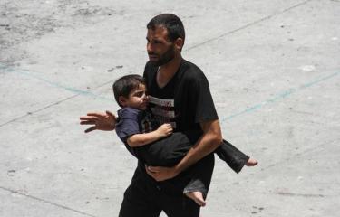   فلسطيني يحاول الهرب مع ابنه من القصف الإسرائيلي على غزة 25 مايو 2024 (رويترز)