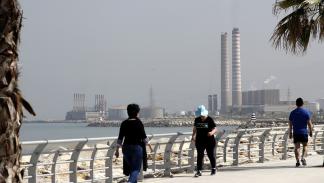 People walk on the seaside promenade with the floating Turkish power station Karadeniz Powership Fatmagul (L) seen in the background next to Lebanon's Zouk Mosbeh power plant, north of the capital Beirut, on April 9, 2019. - The Lebanese cabinet has approved a plan to restructure the country's ailing electricity sector vowing to provide power 24 hours a day from a grid notorious for blackouts. (Photo by JOSEPH EID / AFP) (Photo credit should read JOSEPH EID/AFP via Getty Images)