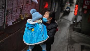 امرأة وطفلها وسط كورونا في الصين (هيكتور ريتامال/ فرانس برس)