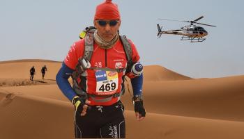 A helicopter flies as competitors take part in the stage 3 of the 35th edition of the Marathon des Sables between Kourci Dial Zaid and Jebel El Mraier in the southern Moroccan Sahara desert on October 5, 2021. - The 35th edition of the marathon is a live stage 250 kilometres race through a formidable landscape in one of the world's most inhospitable climates. (Photo by JEAN-PHILIPPE KSIAZEK / AFP) (Photo by JEAN-PHILIPPE KSIAZEK/AFP via Getty Images)