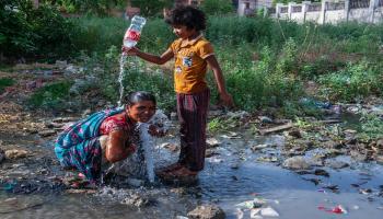 يجمع أطفال الأحياء الفقيرة مياه الشرب من تسرّب أنابيب المياه في مدينة غازي آباد شرق العاصمة دلهي في 12/6/2022 (Getty)