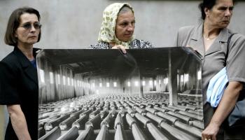 نساء فقدن أفراداً من عائلاتهنّ يحملن صورة لتوابيت بوسنيين راحوا ضحايا لمجزرة سربرنيتسا، لاهاي، 2004 (Getty)