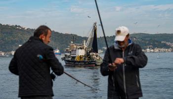 صيادون وسفينة صيد أسماك على ضفة مضيق البوسفور في تركيا (ياسين أكغول/ فرانس برس)