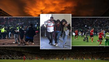 TOPSHOT - In this picture taken on October 1, 2022, a group of people carry a man after a football match between Arema FC and Persebaya Surabaya at Kanjuruhan stadium in Malang, East Java. - At least 127 people died at a football stadium in Indonesia late on October 1 when fans invaded the pitch and police responded with tear gas, triggering a stampede, officials said. (Photo by AFP) (Photo by STR/AFP via Getty Images)