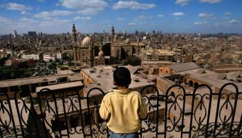 طفلٌ قبالة صروح مملوكية في القاهرة، أبرزها مسجد السلطان حسن (Getty)