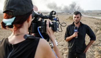 مراسل تلفزيون إسرائيلي على الحدود مع قطاع غزة، 2018 (جاك غويز/فرانس برس)
