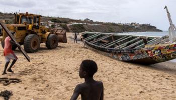 سحب قارب صيد استخدم في رحلة هجرة في السنغال (جون ويسيلز/ فرانس برس)