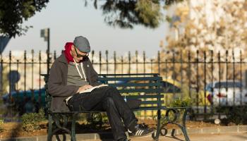 رجل يقرأ كتاباً في ساحة باريس بحيّ اللويبدة في عمّان (Getty)