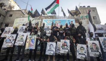 عناصر كتيبة جنين يحملون مجموعة صور لشهداء فلسطين في مخيم جنين (ناصر اشتيه/Getty)